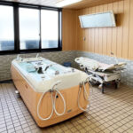 介護浴室。木製の特殊浴槽が2台設置された施設の入浴エリア。